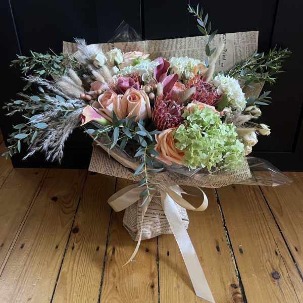 Bouquet of peach and pink roses with green hydrangea and dried grasses