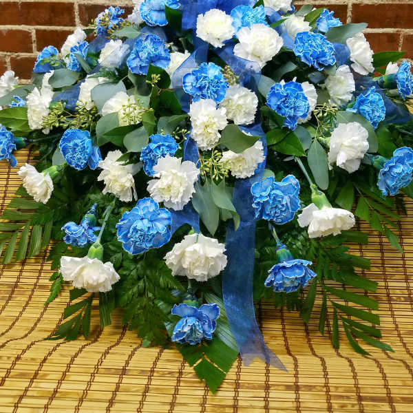 Blue and white carnation arrangement with ribbon on a woven mat