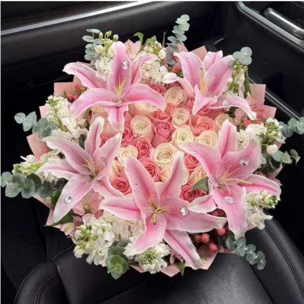 Pink lilies and roses arranged in a bouquet with white accents