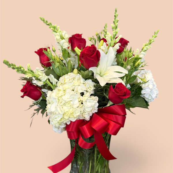 Red roses and white lilies in a glass vase with a red ribbon