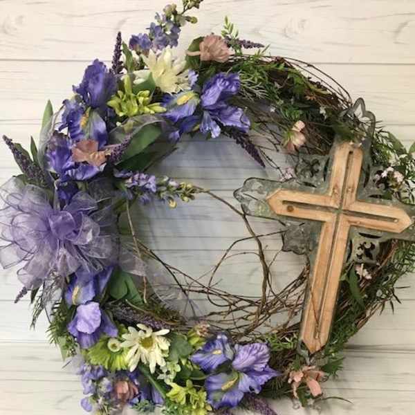 Floral wreath with purple and white flowers and a wooden cross