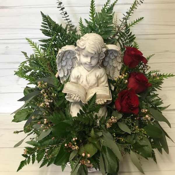 Angel statue surrounded by red roses and greenery