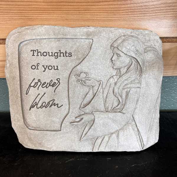 Stone plaque with a woman and the words "Thoughts of you forever bloom"