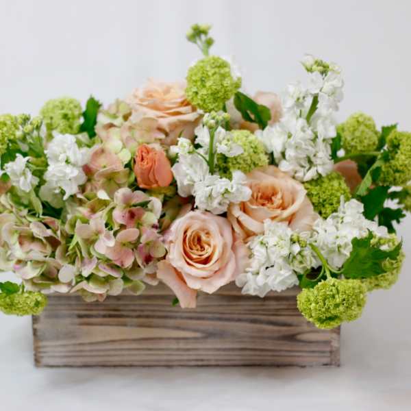 Peach roses and white flowers in a wooden box