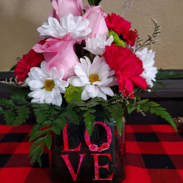 Pink roses and white daisies arranged in a black vase with a LOVE sign