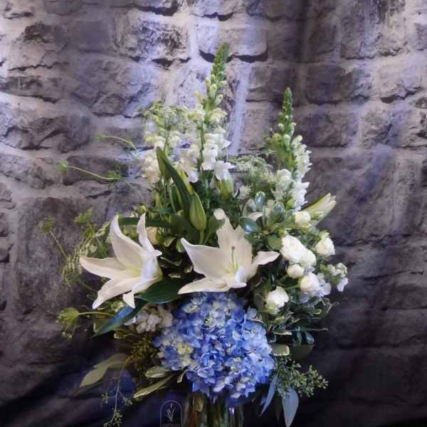 White lilies and blue hydrangeas in a glass vase