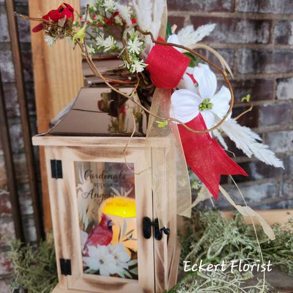 Wooden lantern with a floral spray and red ribbon accents