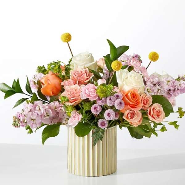 Mixed bouquet of roses and pastel flowers in a gold ribbed vase