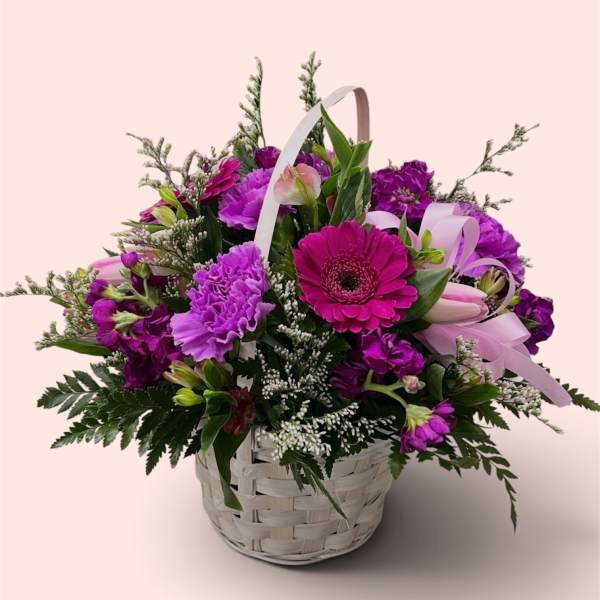 Basket of purple flowers with a pink gerbera daisy and ribbon