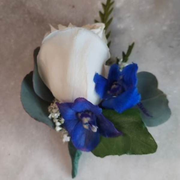 White rose boutonniere with blue flowers and greenery
