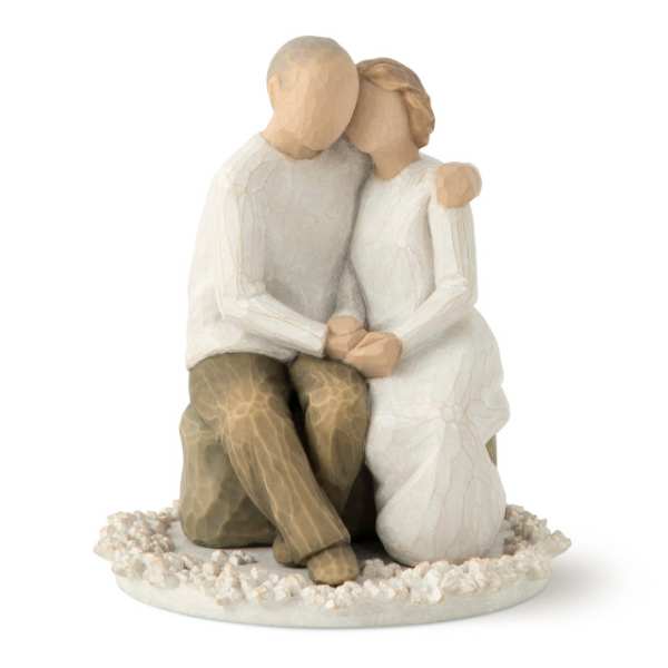 Wooden figurine of a seated couple embracing on a pebble base
