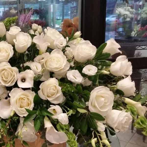 Large white rose arrangement with calla lilies and greenery