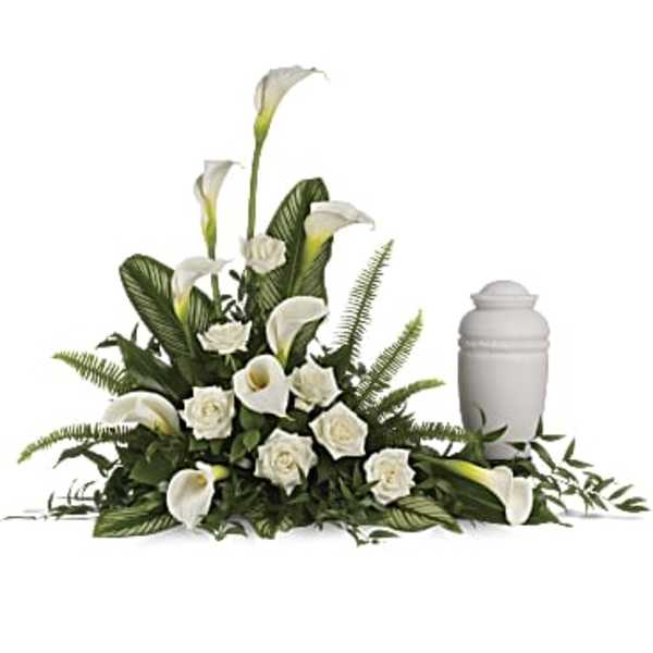 White calla lilies and roses arranged beside a white memorial urn