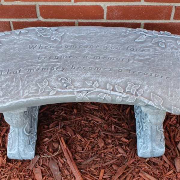 Decorative memorial bench with an engraved quote and floral vine details