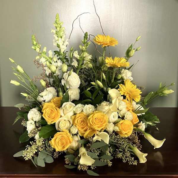 Yellow and white floral arrangement with roses, calla lilies, and daisies