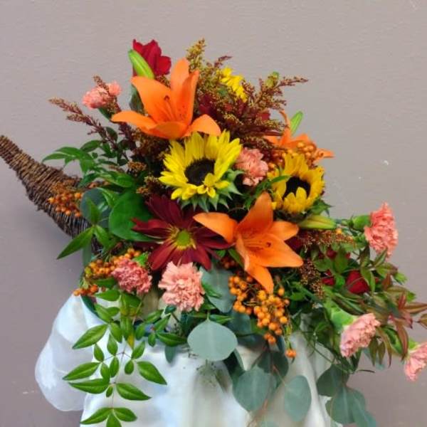 Autumn bouquet with sunflowers, lilies, and carnations in a white wrap