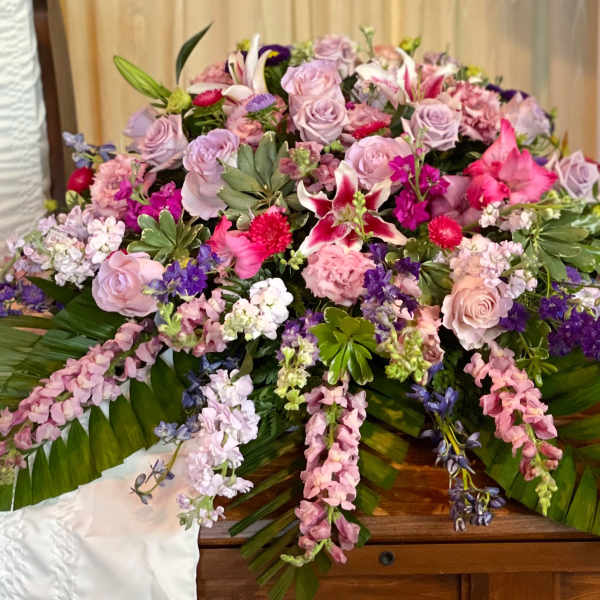 Large pink and lavender floral casket spray with lilies and roses