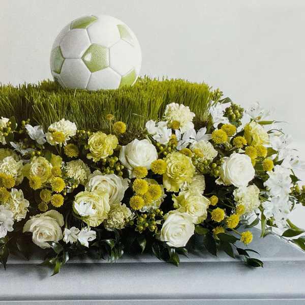 Soccer-themed floral arrangement with white and yellow flowers and a soccer ball topper