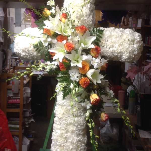 Large white floral cross with orange roses and lilies