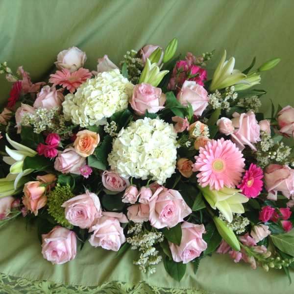Pink roses and lilies arranged with white hydrangeas on green fabric