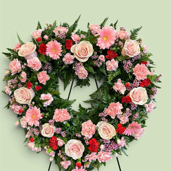 Heart-shaped floral wreath with pink roses, carnations, and daisies
