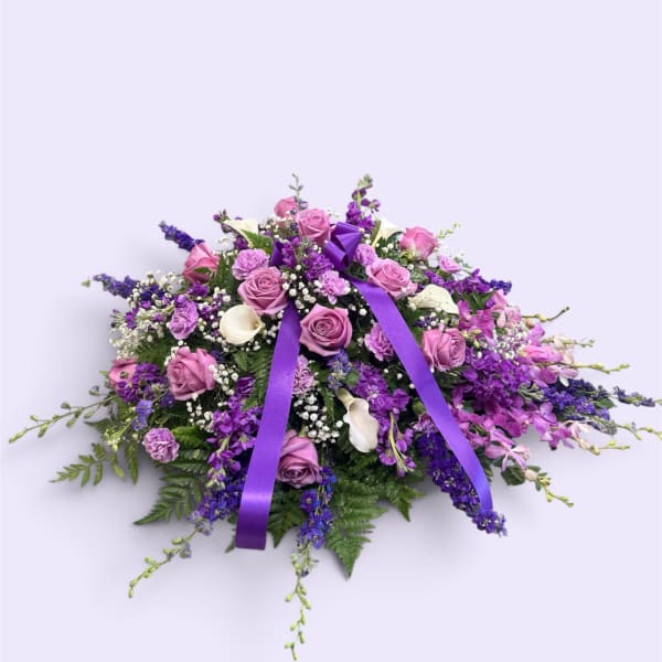 Purple and pink floral casket spray with ribbon accents