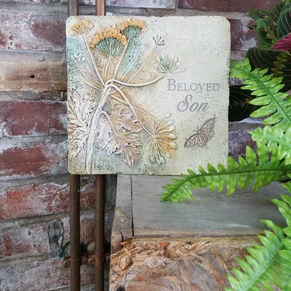 Decorative memorial plaque reading "Beloved Son" with floral relief and butterfly