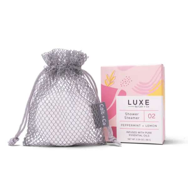 A mesh gift bag beside a pink box labeled shower steamer.