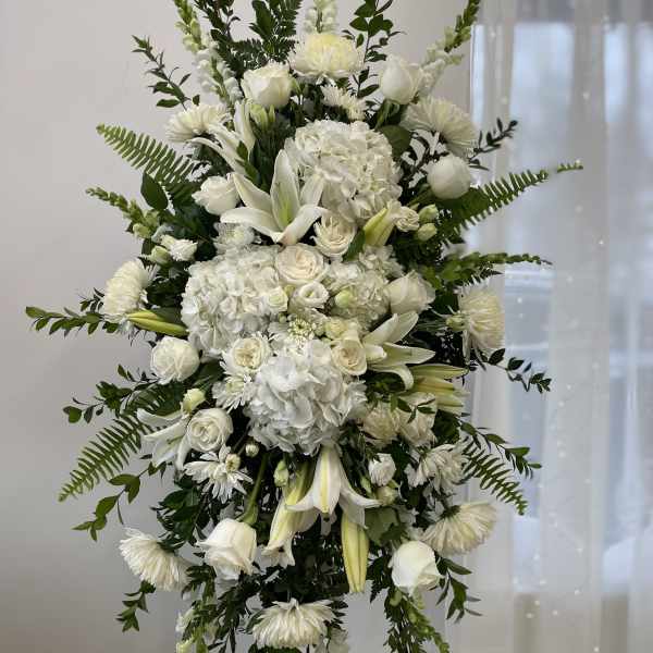 White funeral spray with lilies, roses, and hydrangeas on a stand