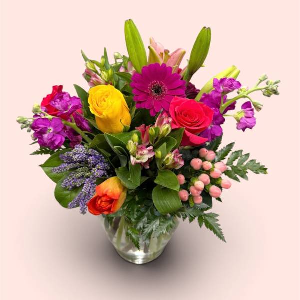 Mixed bouquet of bright flowers in a clear glass vase
