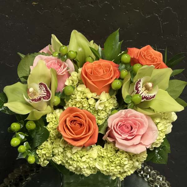 Mixed bouquet of roses, orchids, and hydrangeas in a glass vase