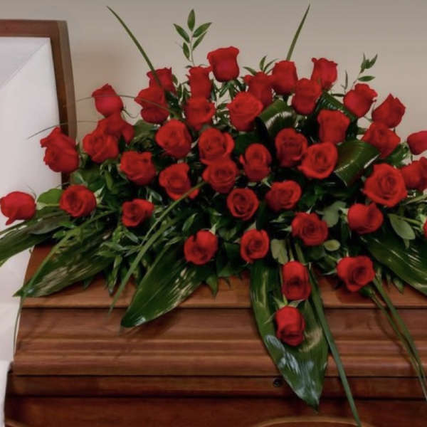 Large arrangement of red roses on a wooden casket