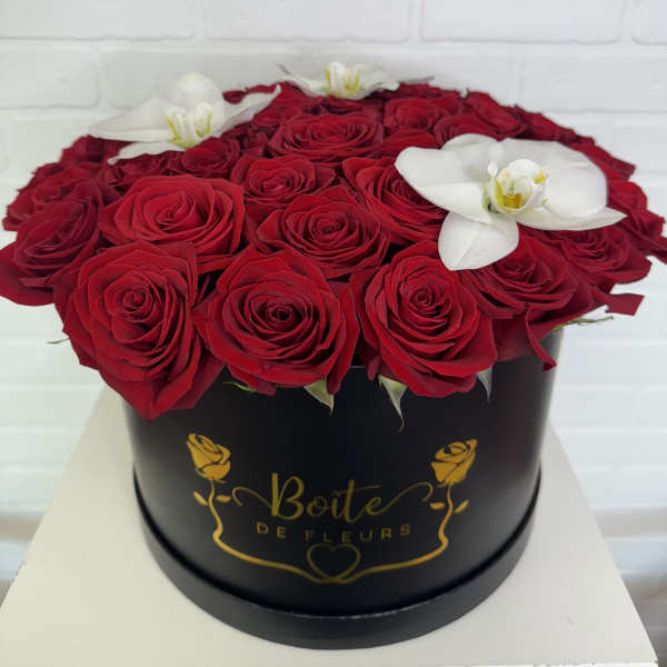 Red roses and white orchids arranged in a black round box