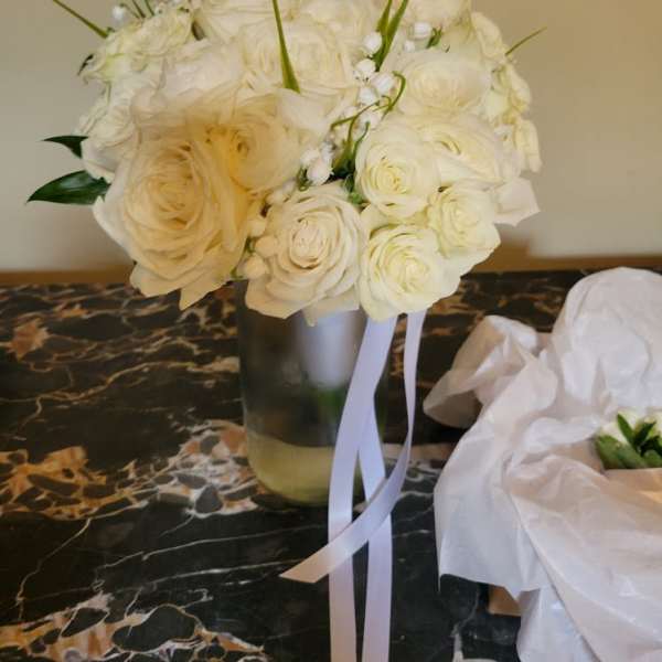 White rose bouquet in a glass vase with ribbon streamers