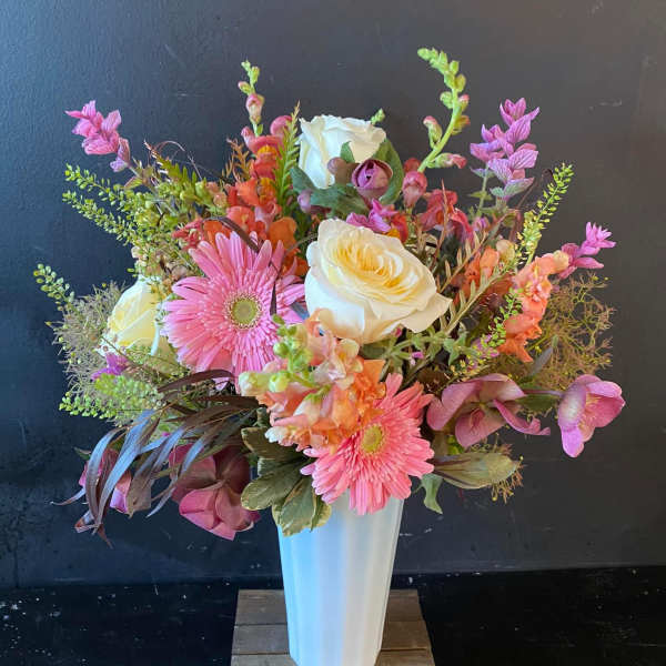 Pink and white mixed flower arrangement in a tall white vase
