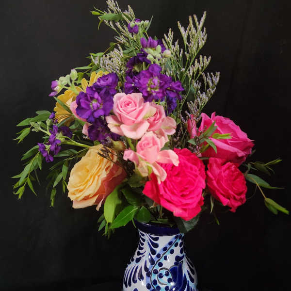 Mixed bouquet of pink, purple, and yellow flowers in a patterned vase