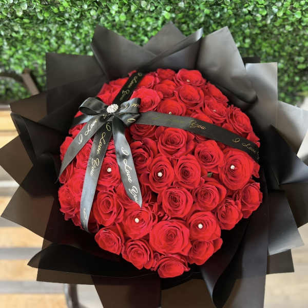 Large bouquet of red roses wrapped in black paper with a black ribbon