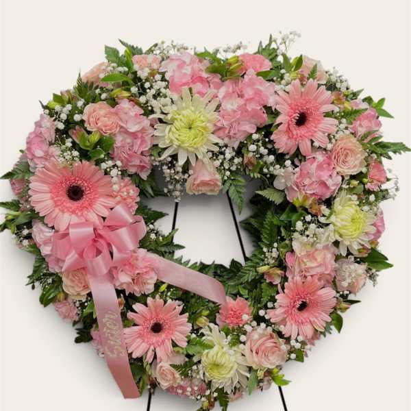 Heart-shaped pink floral wreath with a ribbon bow