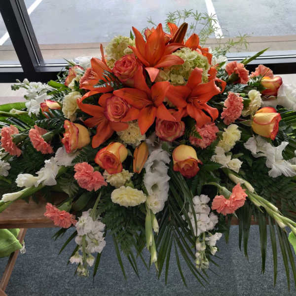 Large floral casket spray with orange lilies and roses