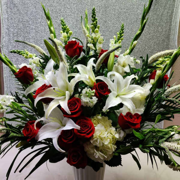 Red roses and white lilies in a tall white vase
