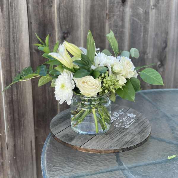 White flowers and pale yellow lilies in a clear glass vase