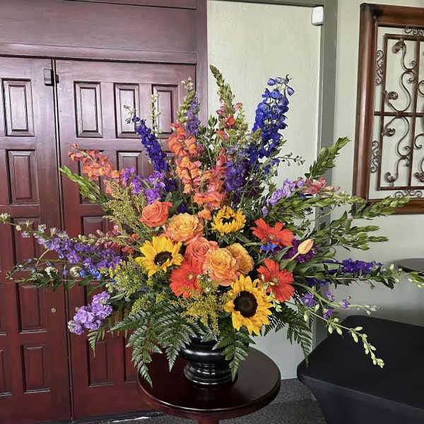 Large colorful floral arrangement in a black vase on a round table