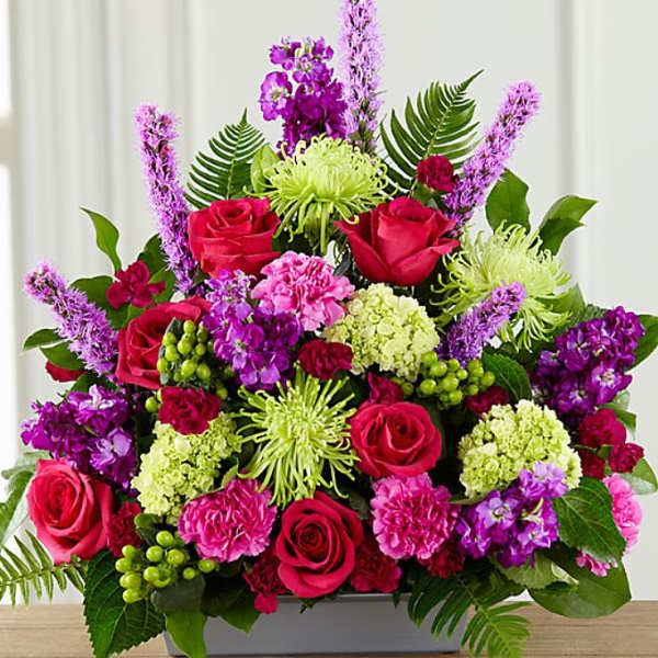 Mixed bouquet of pink roses, purple blooms, and green flowers in a rectangular vase
