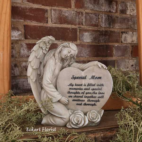 Angel figurine holding a heart-shaped memorial plaque with roses