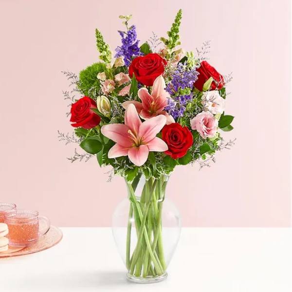 Bouquet of red roses and pink lilies in a clear glass vase
