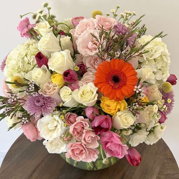 Mixed bouquet of pink, white, and yellow flowers in a glass vase