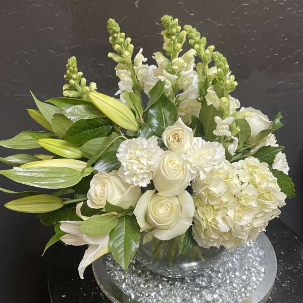 White roses and lilies arranged in a clear glass vase