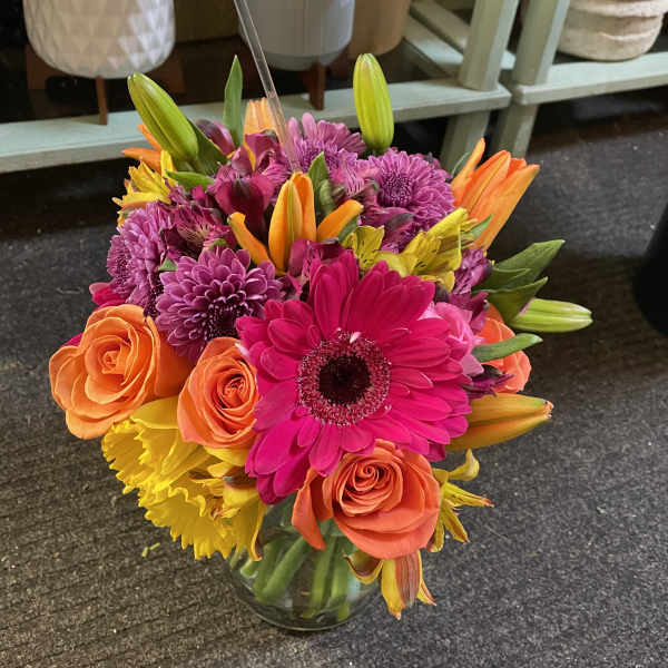 Bright mixed bouquet of pink, orange, and yellow flowers in a glass vase