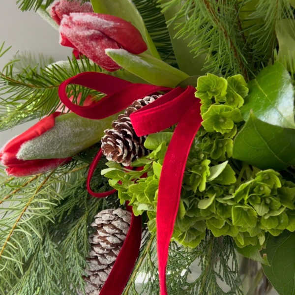 Holiday bouquet with red tulips, pinecones, and evergreen foliage