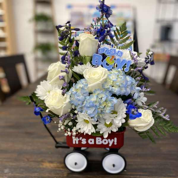 Blue and white flower arrangement in a wagon with an "It's a Boy!" sign